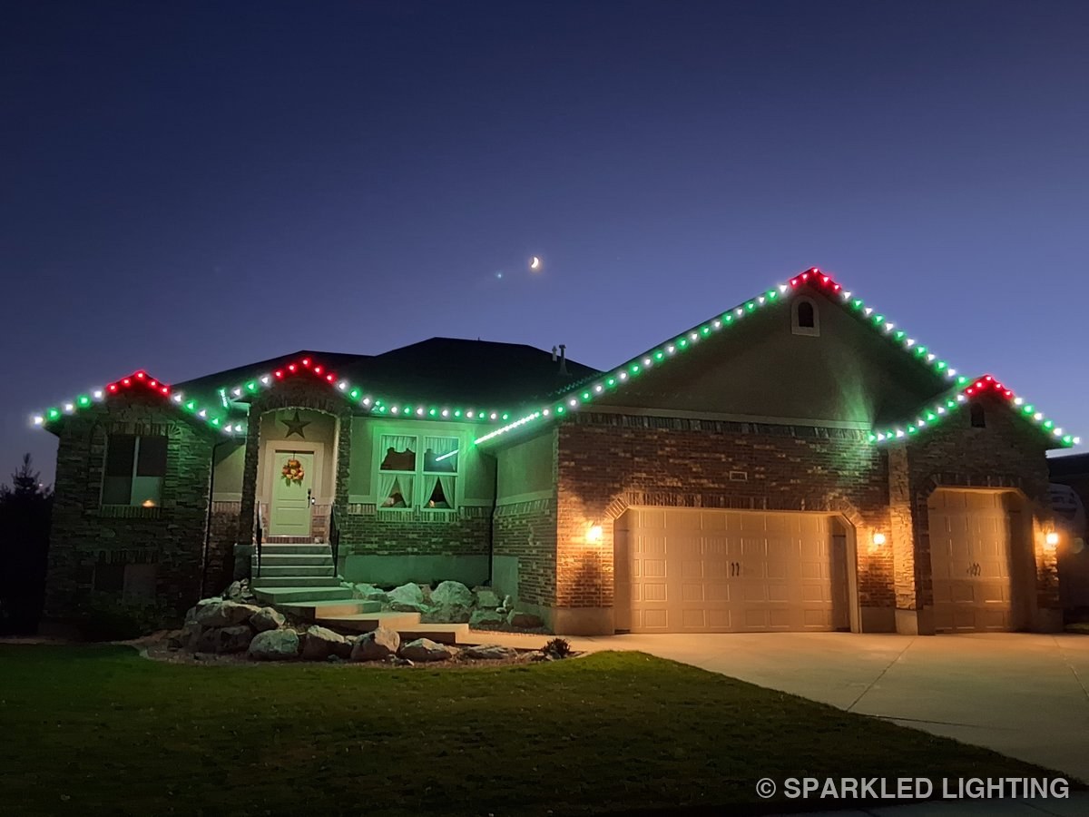 Christmas lights in green, red and warm white on a stone two story Farr West Utah home