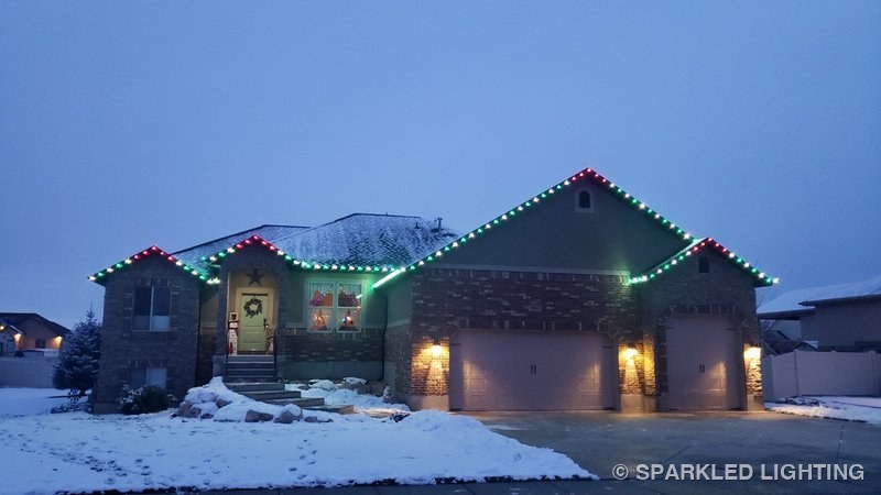 Christmas lights installed on a single story house on a Plain City Utah home in green and red