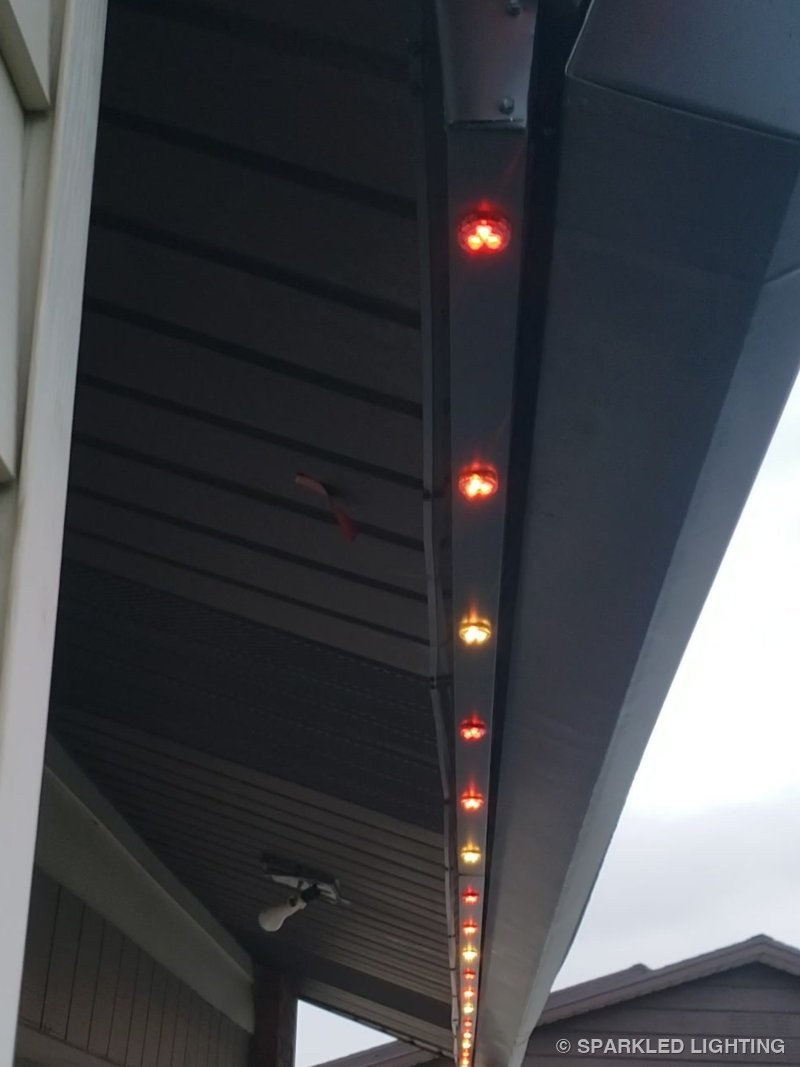 The same custom channel at dusk with red and amber LED pucks glowing below the oversized gutter in Roy Utah
