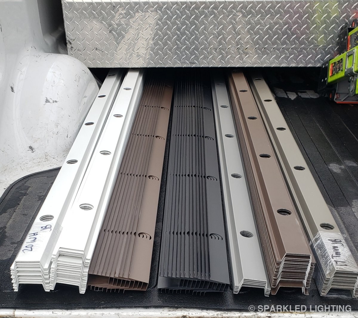 Six colors of color-matched aluminum channel stacked and ready for permanent lighting installs
