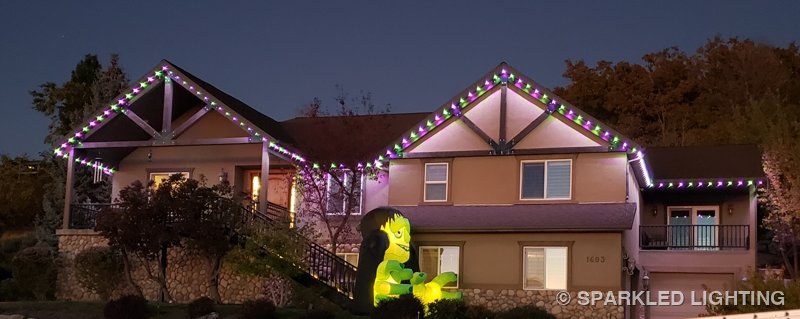 A hillside Bountiful Utah home with permanent LED lights in purple and green for Halloween