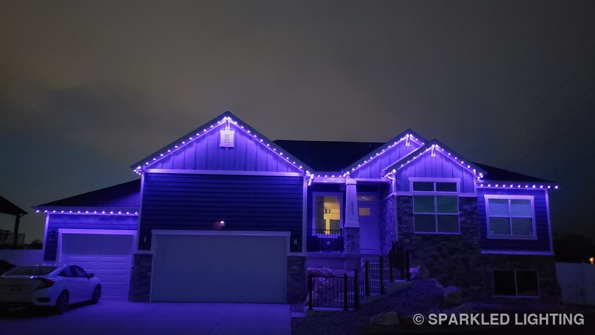 A single-story Farr West UT home at night with Sparkled Lighting permanent LED lights in a striking full purple — Halloween or year-round accent