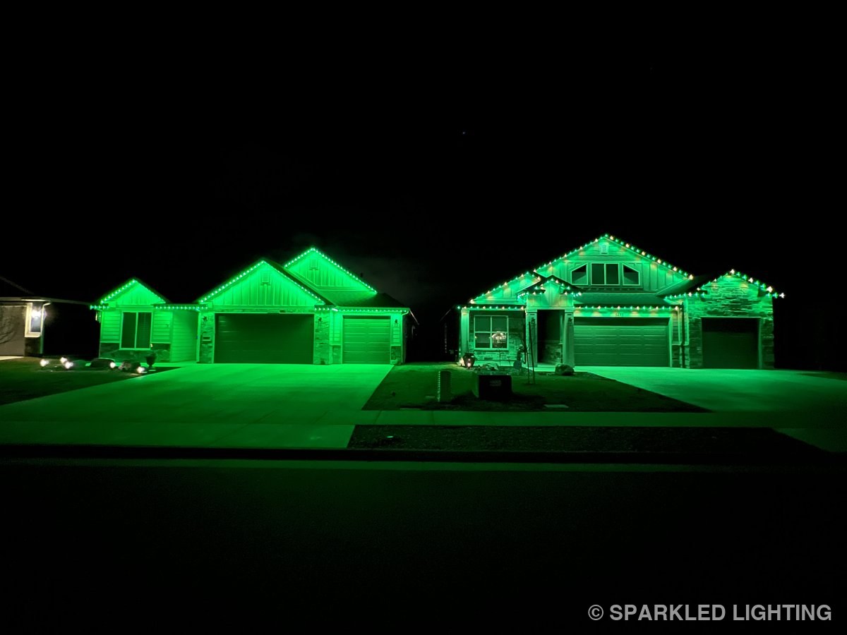 Two neighboring Hooper Utah homes lit green with permanent LED lights