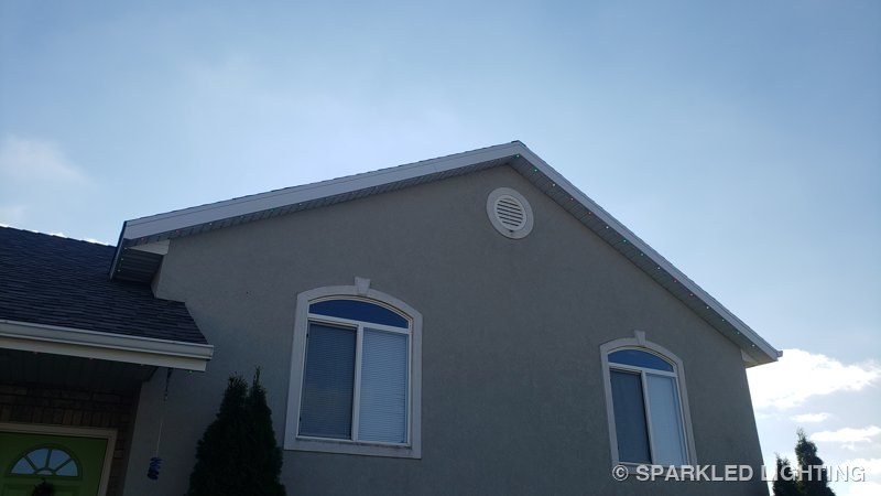 Red and green SmartClip LED bulbs visible by day along a Plain City Utah gable
