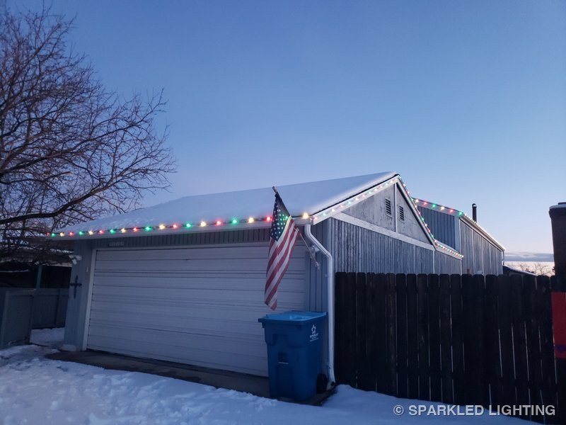 SmartClip LED lights in red and green on a snowy Ogden Utah garage gable